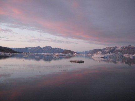 Sun setting over Sermilik Fjord into which Helheim Glacier forms or "calves" large amounts of icebergs each summer. A recent surge of icebergs produced by Helheim Glacier in Greenland has only been exceeded once in more than a century. Scientists suggest that this establishes a role for climate in calving from glaciers – one that suggests that it will increase as temperatures rise. Credit: Camilla S. Andresen.
